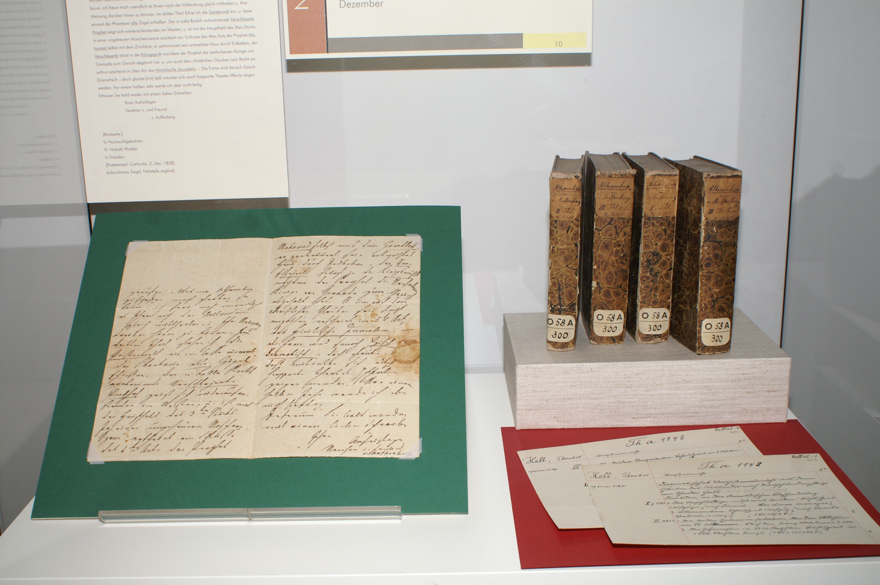 Der Brief von Joseph von Auffenberg ist aufgezogen auf grüner Pappe, rechts hinten sind vier Bände des Almanach.