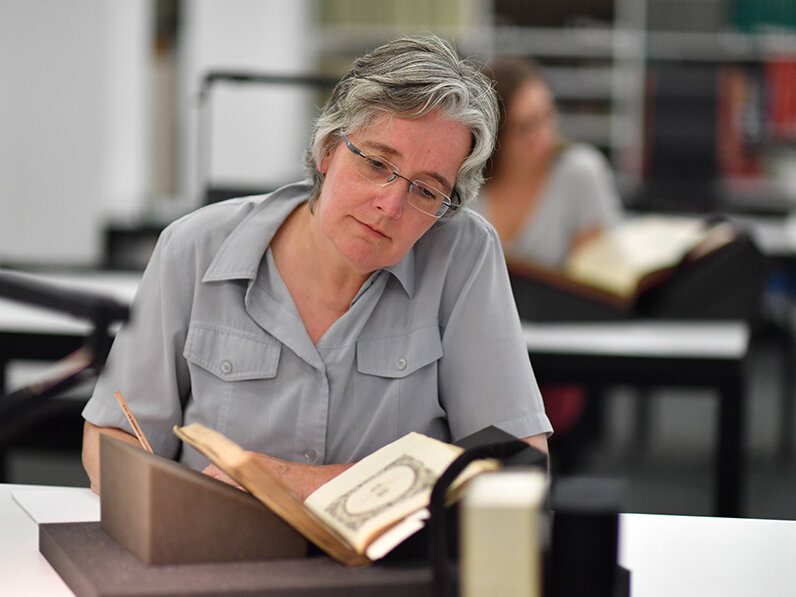 Eine Forscherin arbeitet im Lesesaal Sammlungen mit einem kleinformatigen Band aus dem historischen Buchbestand der Badischen Landesbibliothek.