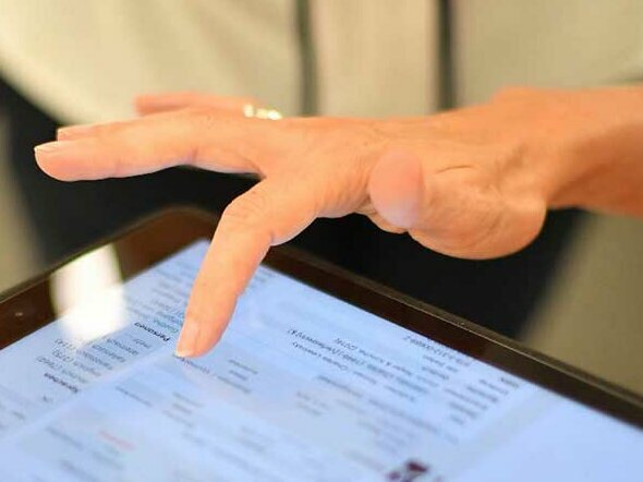 © Foto: Badische Landesbibliothek Karlsruhe Das Bild ist eine Detailansicht einer Hand, deren Zeigefinger auf dem Bildschirm eines Tablets ein Werk aus der Ergebnisliste des Katalog plus auswählt.