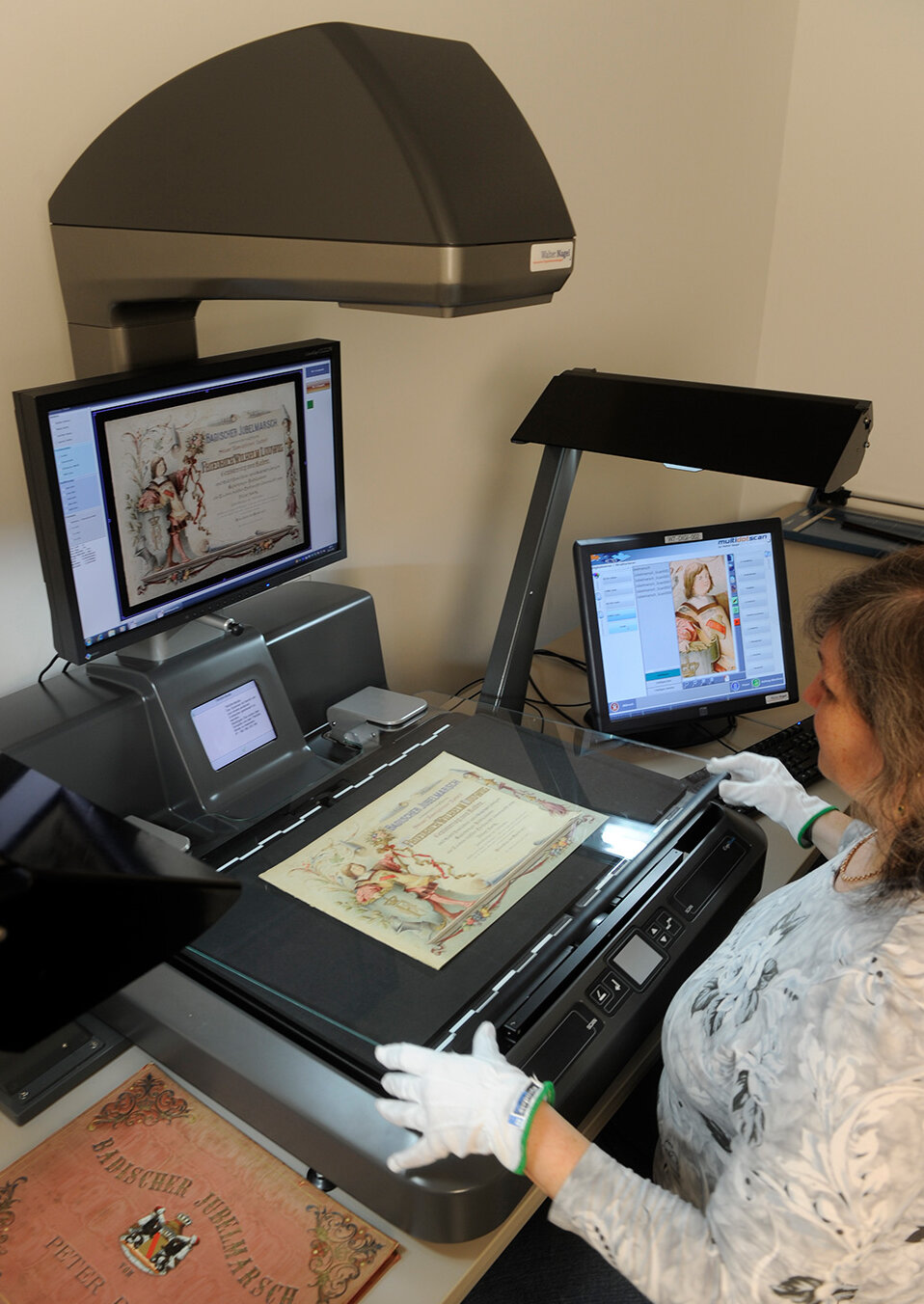 Eine Mitarbeiterin der Digitalisierungswerkstatt digitalisiert an einem Buchscanner historisches Material.