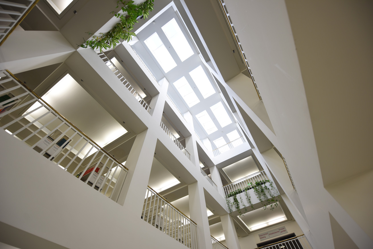Das Bild zeigt einen der Lichthöfe des Bibliotheksgebäudes, vom Foyer aus in extremer Untersicht fotografiert.