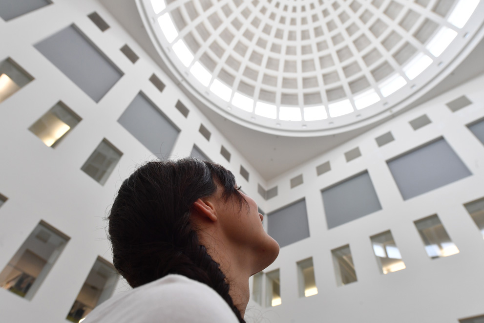Das Bild zeigt in extremer Untersicht eine Frau, die interessiert nach oben blickt und sich die Kuppel im Lesesaal der Badischen Landesbibliothek ansieht.