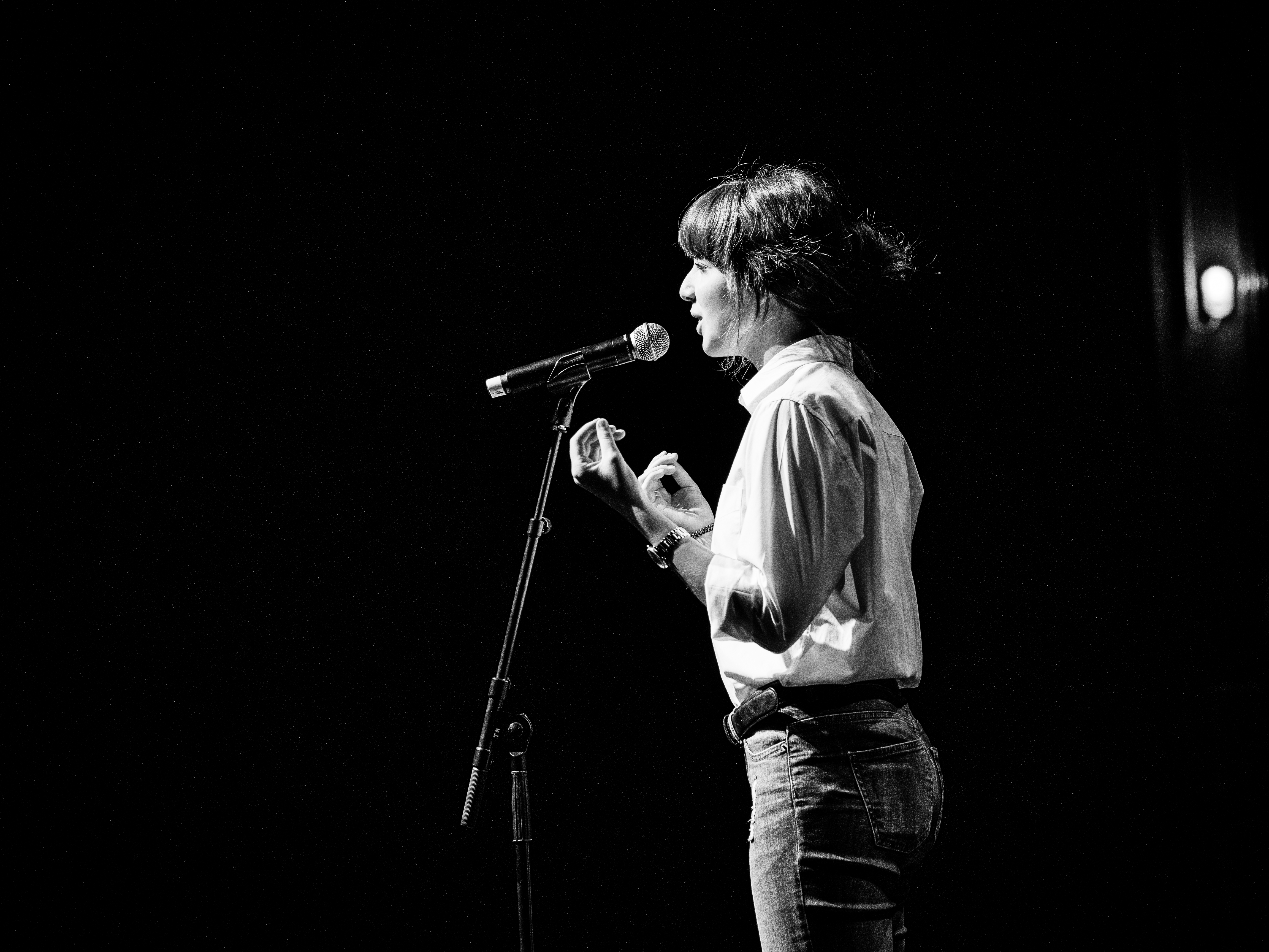 Die schwarz-weiß Fotografie zeigt Natalie Friedrich am Mikrofon stehend.