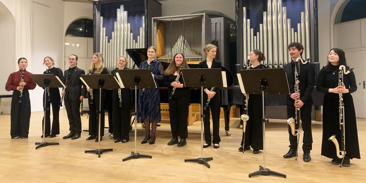 Zu sehen ist die Klarinettenklasse bei einem Konzert. Im Hintergrund ist eine Orgel zu erahnen.
