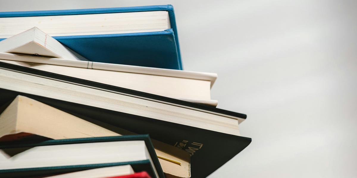 Zu sehen ist ein Bücherstapel, der leicht schräg von unten fotografiert wurde.