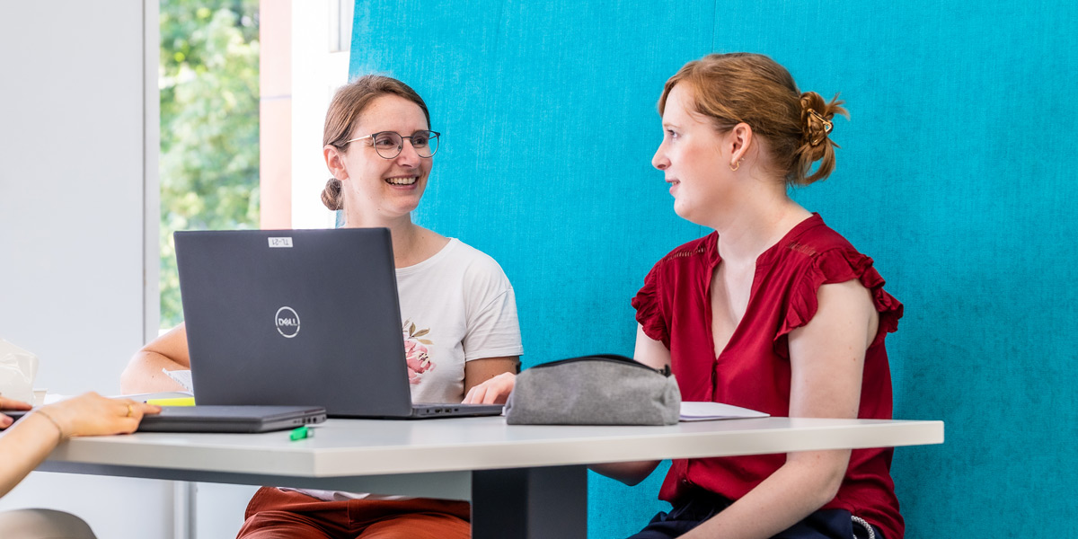 Zwei junge Frauen sitzen einer Lernkoje der BLB vor einem Laptop.