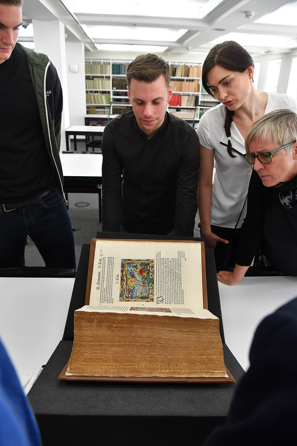 © Foto: Uli Deck Im Bild sind mehrere Personen zu sehen. Diese gruppieren sich um ein historisches Buch und betrachten dieses.