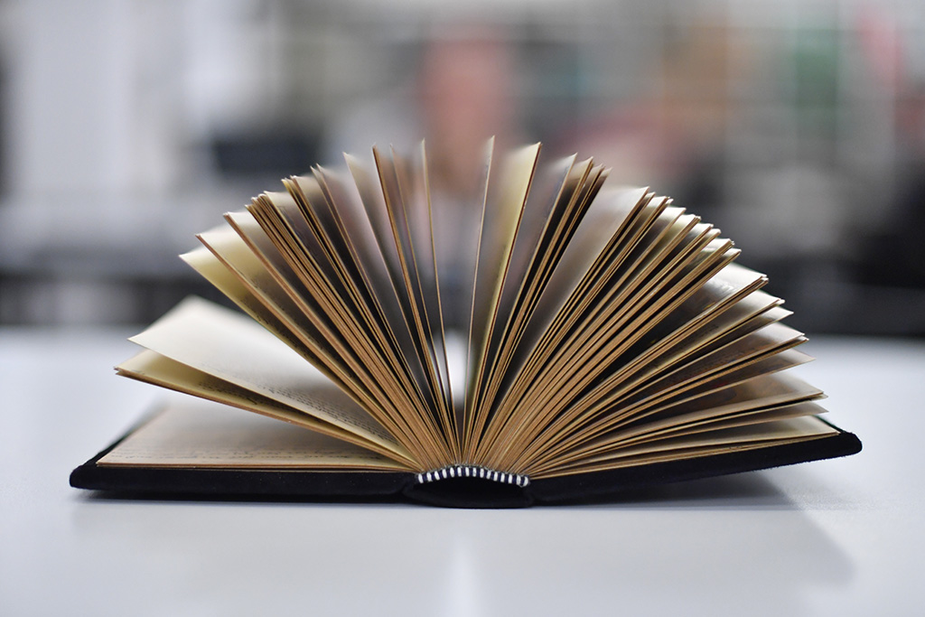 Ein historisches Buch liegt auf einem Tisch im Lesesaal Sammlungen und seine Seiten blättern sich wie ein Fächer auf.