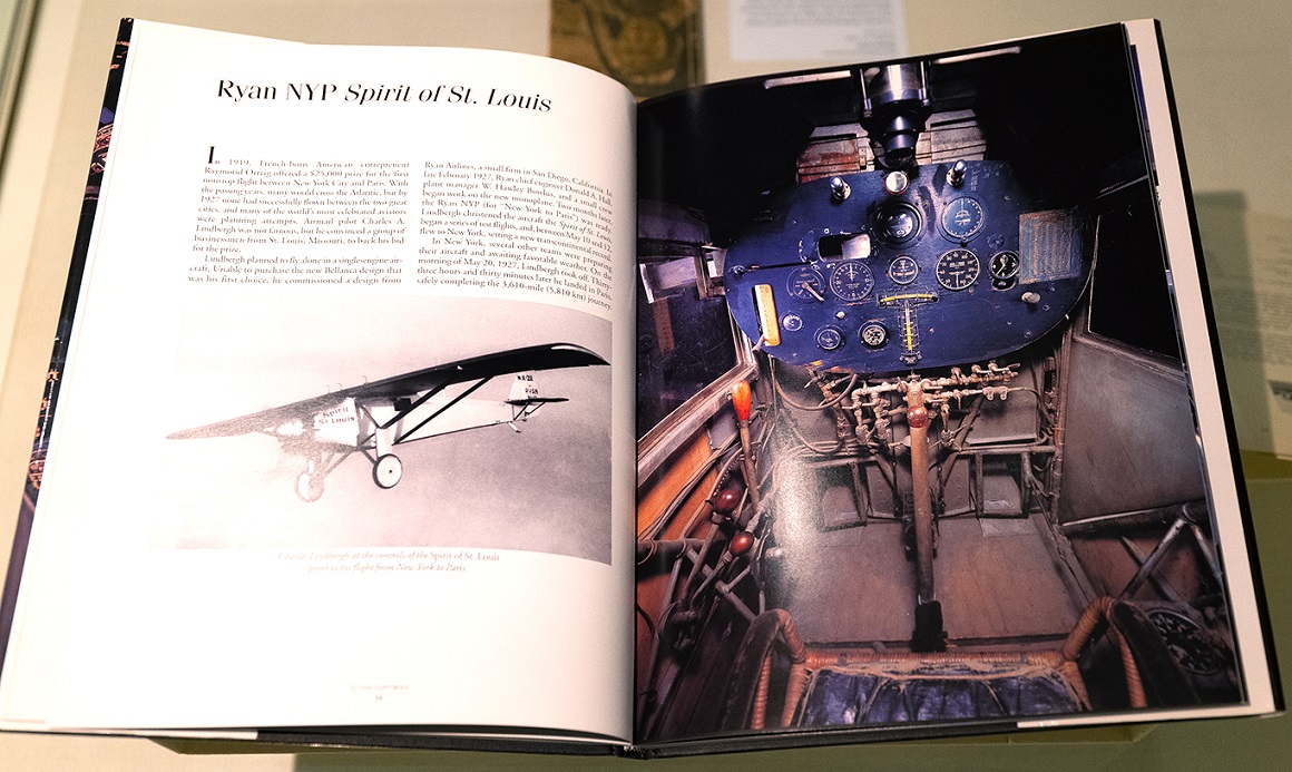 Aufgeschlagenes Buch mit Fotografie eines Flugzeugs (links) und eines Cockpits (rechts)