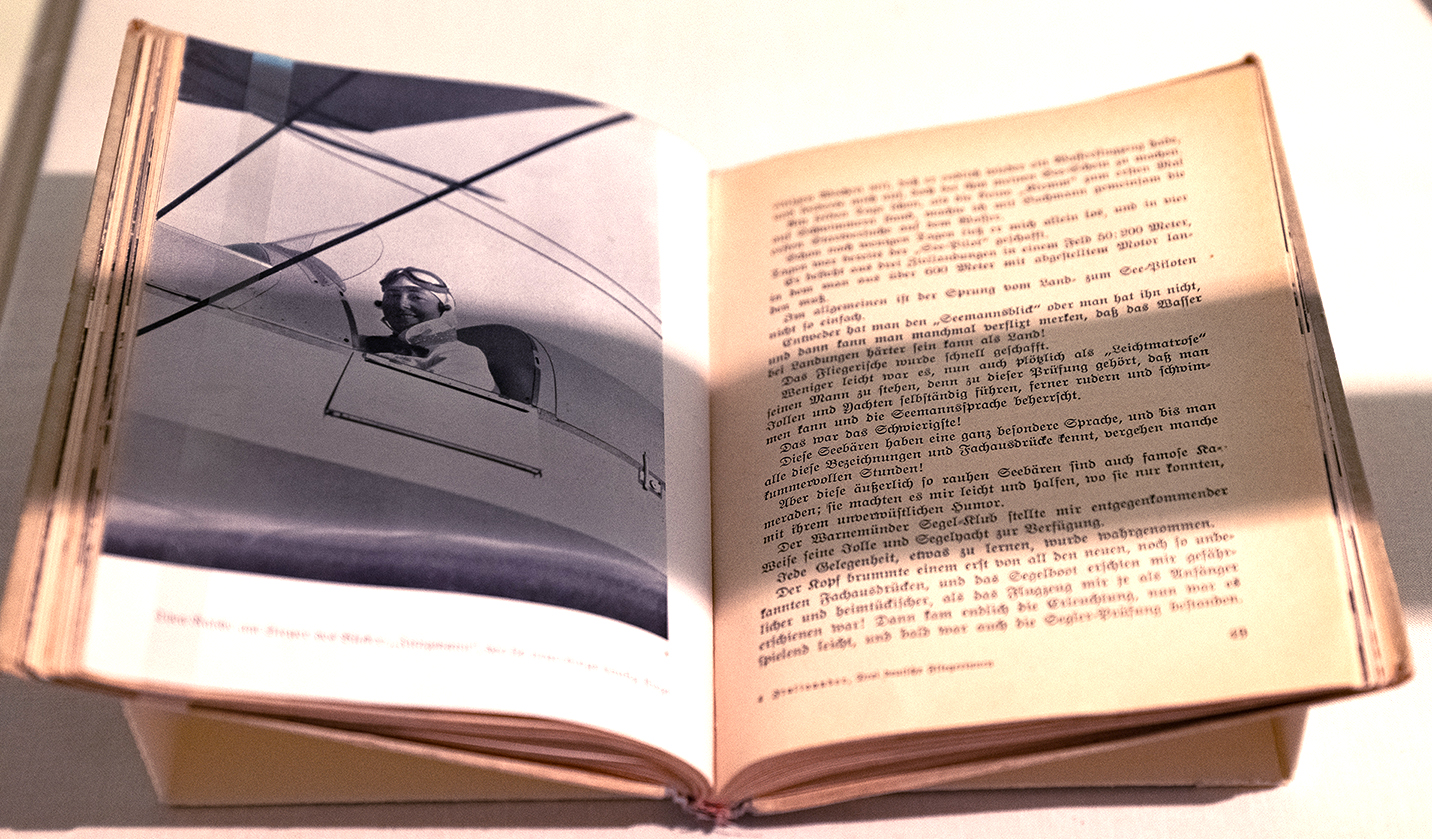Aufgeschlagenes Buch mit Schwarz-Weiß-Porträt einer Pilotin im Flugzeug