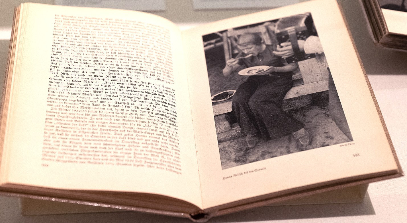 Aufgeschlagenes Buch mit Schwarz-Weiß-Porträt einer essenden Pilotin