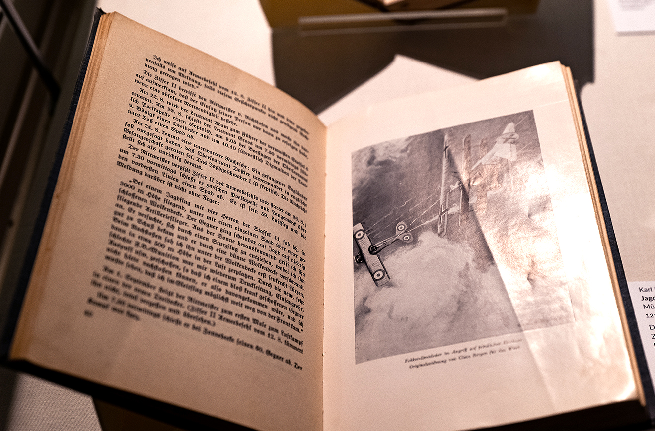 Geöffnetes Buch mit Schwarz-Weiß-Darstellung eines Luftkampfes zweier Flugzeuge