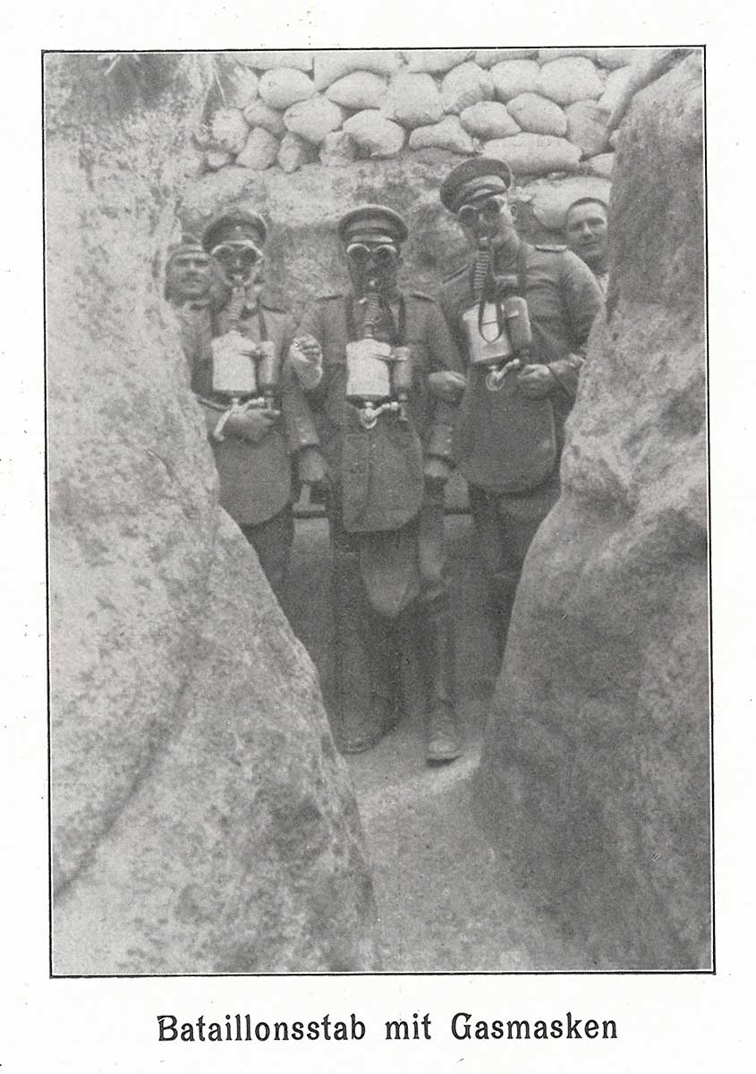 Schwarz-weiße Fotografie von Soldaten im Graben, die Gasmasken aufhaben.