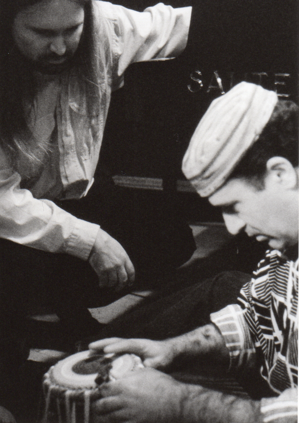 Schwarz-weiß Foto von Hakim Ludin an einer Tabla und Joachim Krebs der ihn beobachtet.
