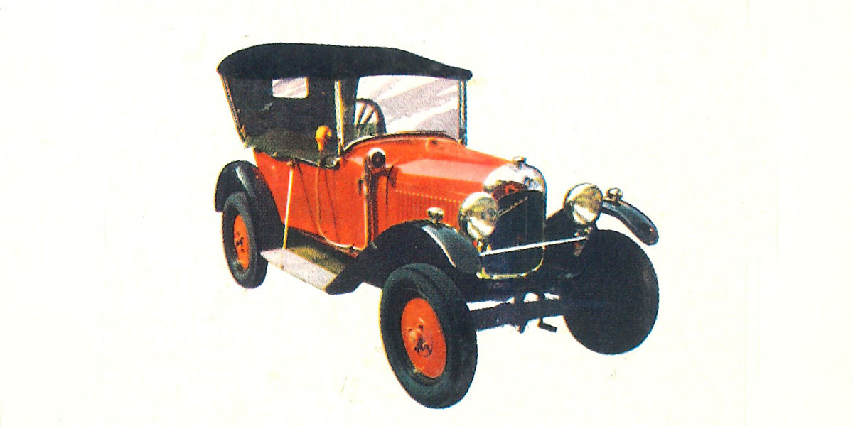 Abgebildet schwarz-roter Oldtimer. Bei dem Modell handelt es sich um einen Citroën Typ-A, das Automobil besitzt ein kompaktes, elegantes Design mit geschwungener Karosserie. Es hat runde Scheinwerfer, ein offenes oder geschlossenes Dach.