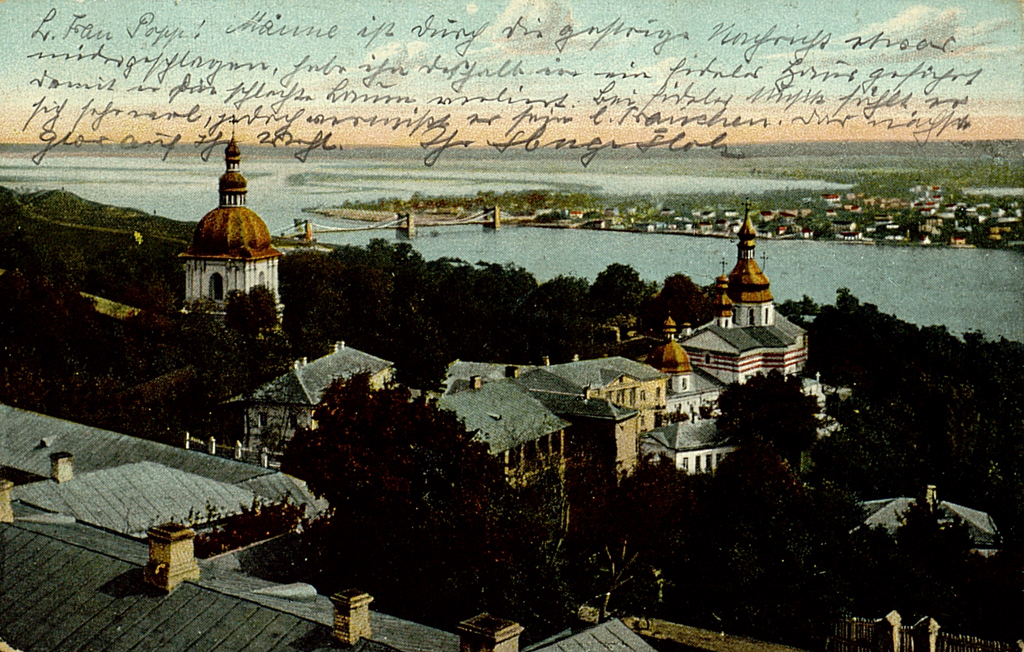 Das Bild zeigt eine kolorierte Stadtansicht von Kiew. Es handelt sich um eine 1918 gelaufene Postkarte. Im Vordergrund sind zahlreiche Architekturen erkennbar. Im Hintergrund der Dnepr. 