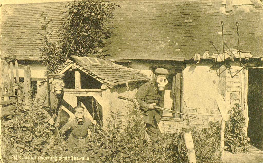 Zu sehen sind drei Soldaten der Infanterie. Sie tragen allesamt Gasmasken und rechnen laut Beschreibung mit einem Gasangriff. 