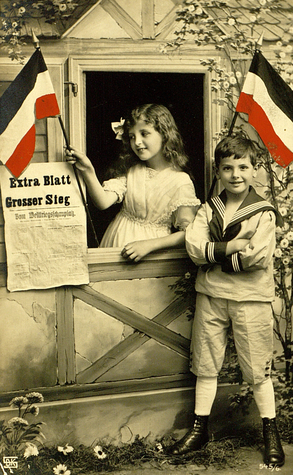 Handkolorierte Foto-Postkarte mit Kindern mit Reichsfahnen und einer Zeitung "Extra Blatt. Grosser Sieg"