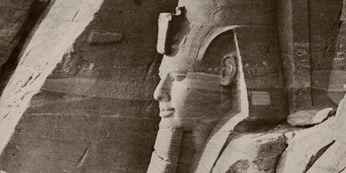 Ausschnitt aus einer Fotografie von August Lorent. Der Fokus liegt auf einer, aus Stein gemeißelten, Pharaostatue.