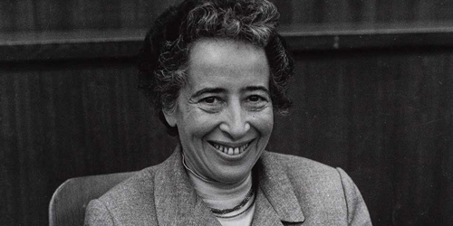 Portraitfoto von Hannah Arendt, die dem Fotografen zulächelt.