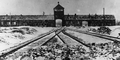 Das Foto zeigt das Konzentrationslager Auschwitz, Polen 1945. Lagertor (innen) / Ausfahrt nach der Befreiung, im Vordergrund von den Wachmannschaften zurückgelassene Ausrüstungsgegenstände.
