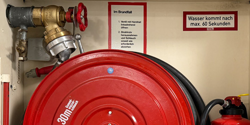 Innenansicht eines Brandschutzschranks mit Feuerlöscher und Schlauch