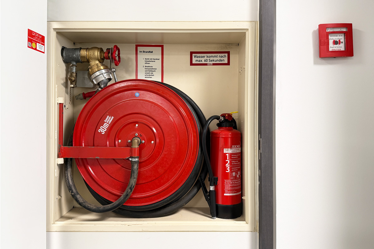 Innenansicht eines Brandschutzschranks mit Feuerlöscher und Schlauch