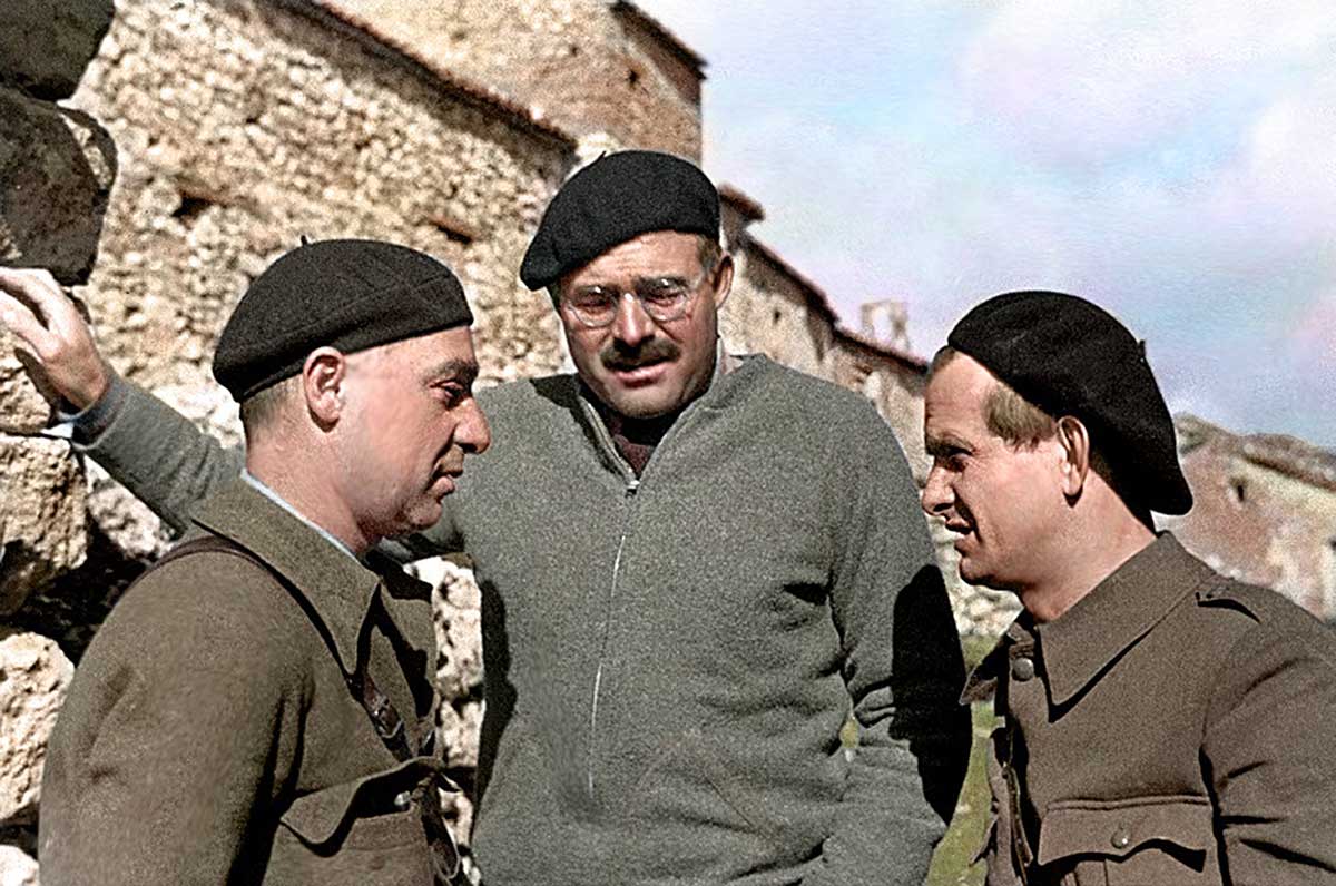 Zu sehen ist eine Fotografie der Autoren Gustav Regler, samt seinen Kollegen Ernest Hemingway und Ilja Ehrenburg. Sie tragen schwarze Baskenmützen, um ihre Zugehörigkeit zur internationalen spanischen Brigade zu zeigen.