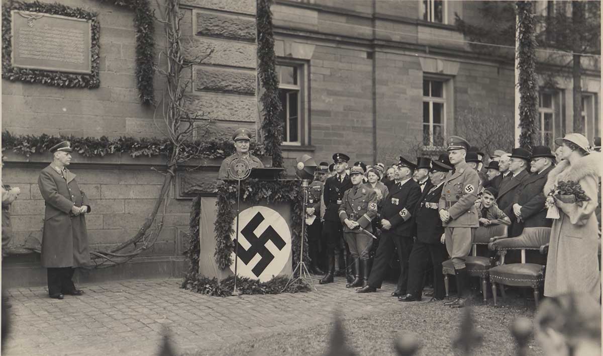 Zu sehen ist eine schwarz-weiße Fotografie einer Rede von Hermann Göring, am Rednerpult.