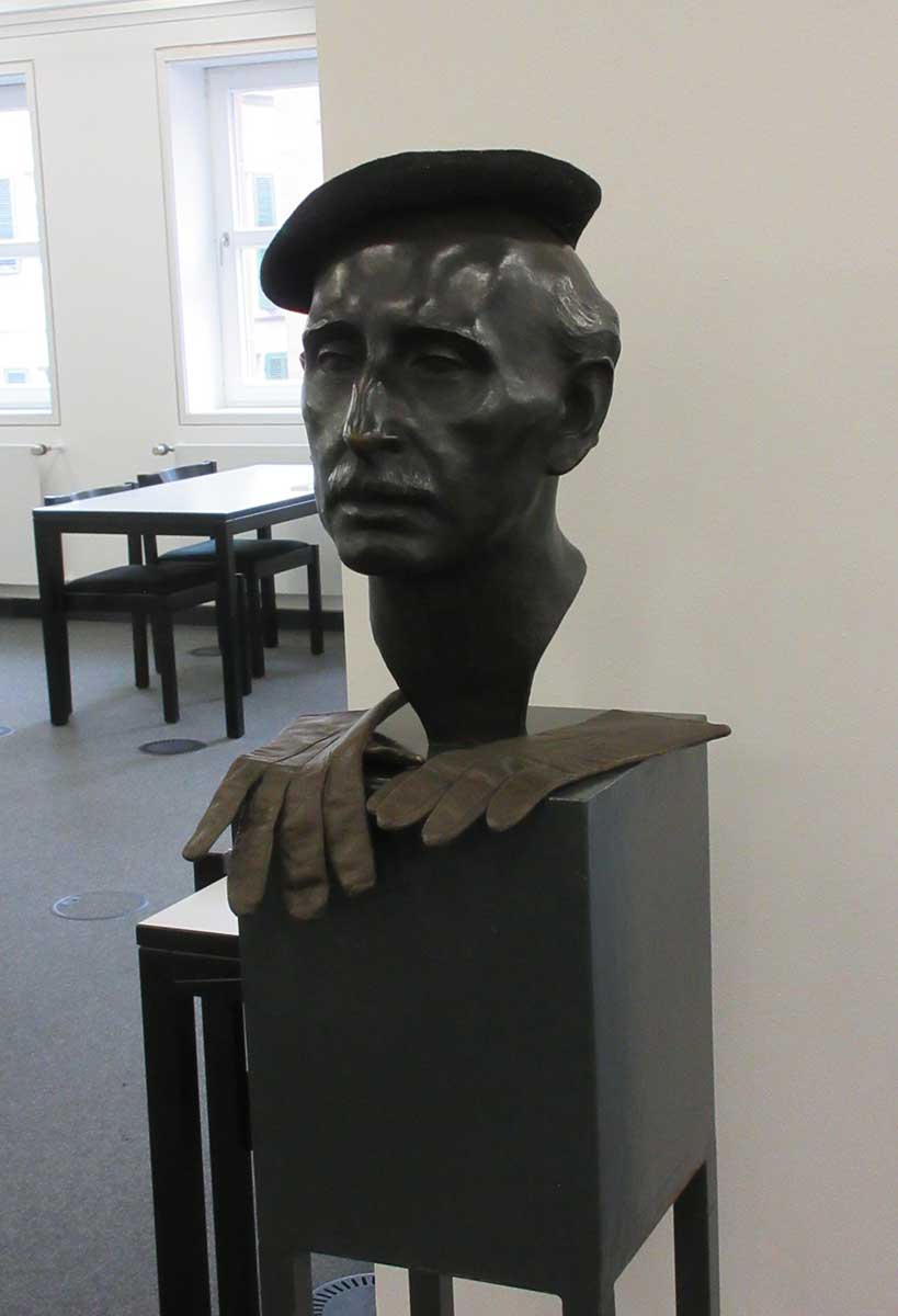 Zu sehen ist Arthur Zweinigers Alfred Mombert-Büste, die mit Baskenmütze und Handschuhen geschmückt wurde.