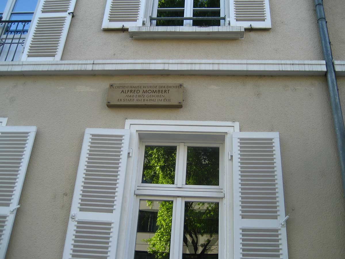 Zu sehen ist eine Gedenktafel an der Fassade von Alfred Momberts Geburtshaus in der Kaiserstraße.