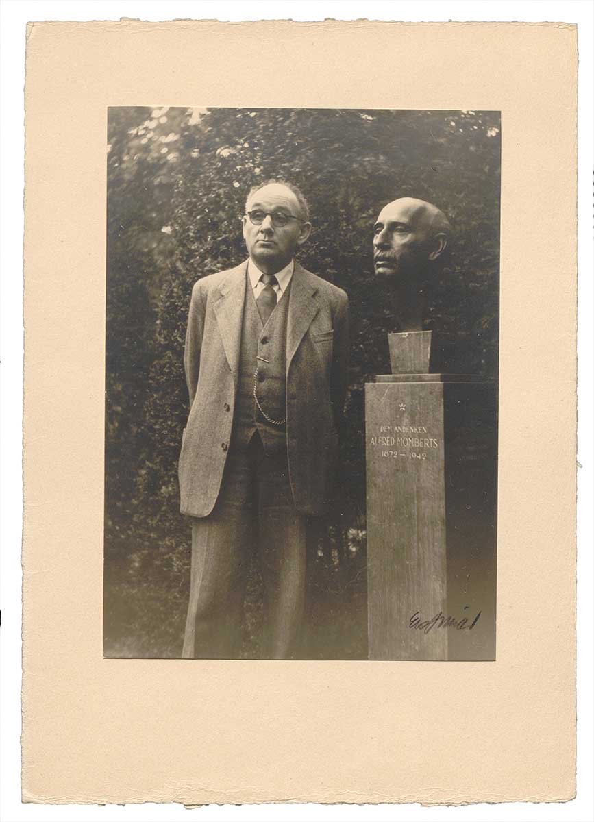 Zu sehen ist eine Fotografie, die Hans Reinhart neben der Alfred Mombert-Büste zeigt.