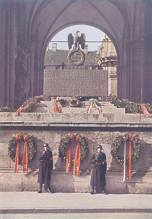 Zu sehen ist das Denkmal für die getöteten Teilnehmer des Hitlerputsches in der Münchener Feldherrnhalle. Zwei NS-Soldaten stehen Wache. 