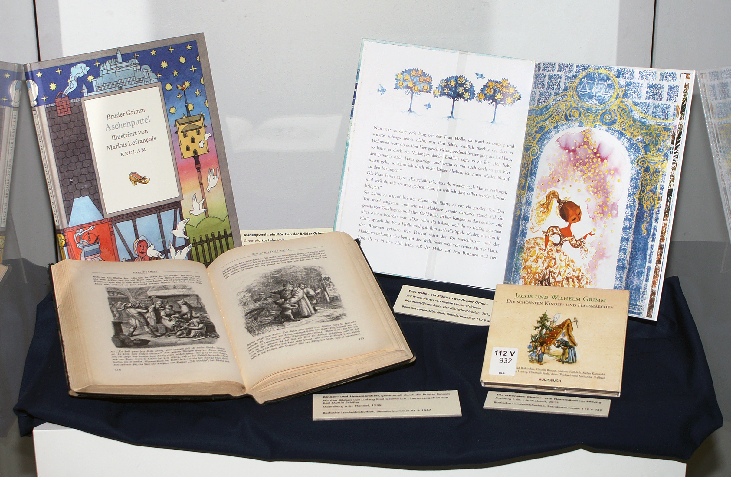 Ausgestellt sind vier Märchenbüchern aus den letzten zwei Jahrhunderten, die Seiten sind unterschiedlich illustriert in Farbe und Schwarz-Weiß.