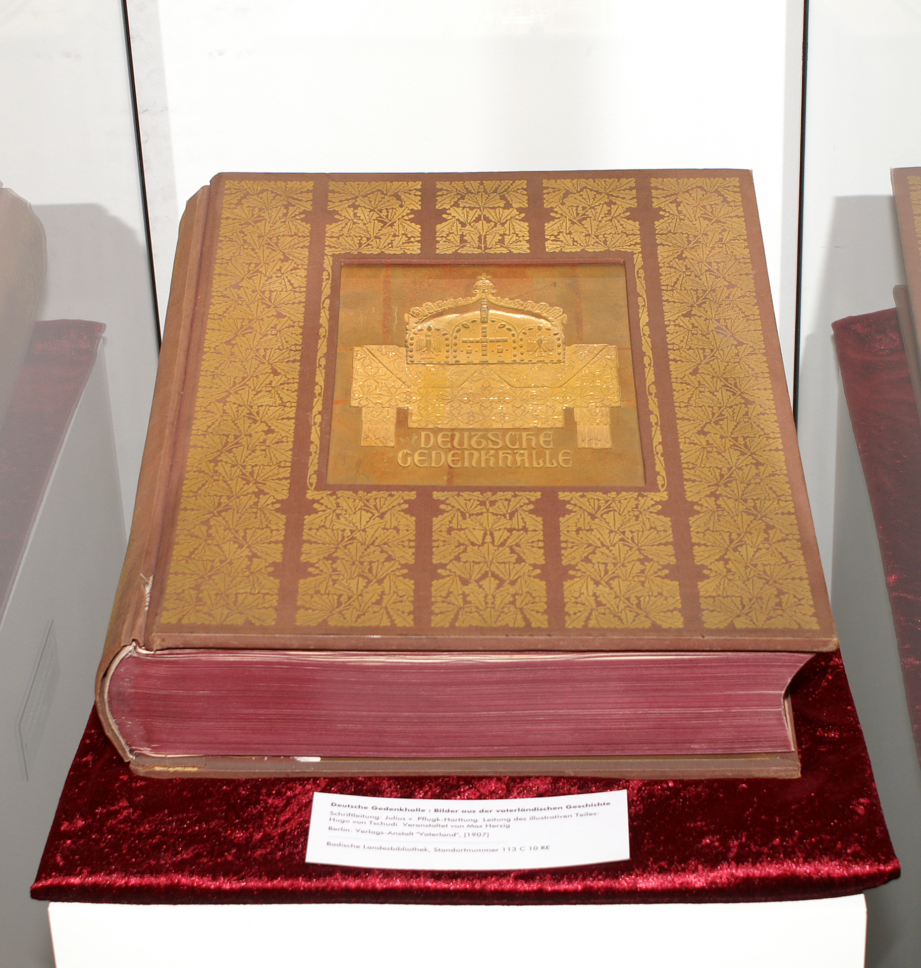 Ausstellungsansicht des Buches "Deutsche Gedenkhalle". Das Buch ist rot mit goldenen Prägungen. Der Schnitt ist dunkelrot.